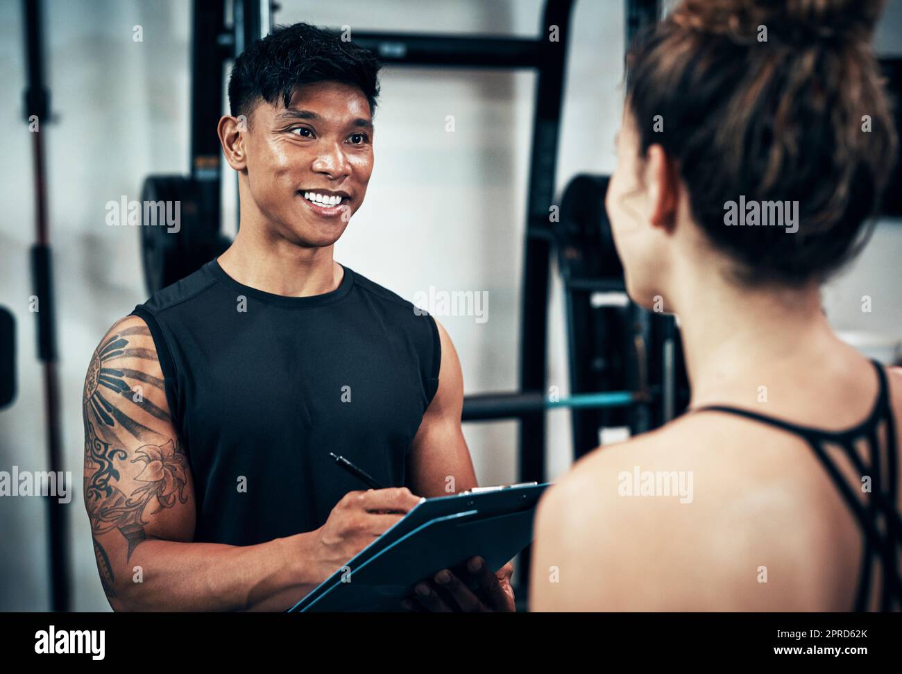 Lets just do a quick body assessment. a sporty young woman talking to a fitness trainer at the gym. Stock Photo