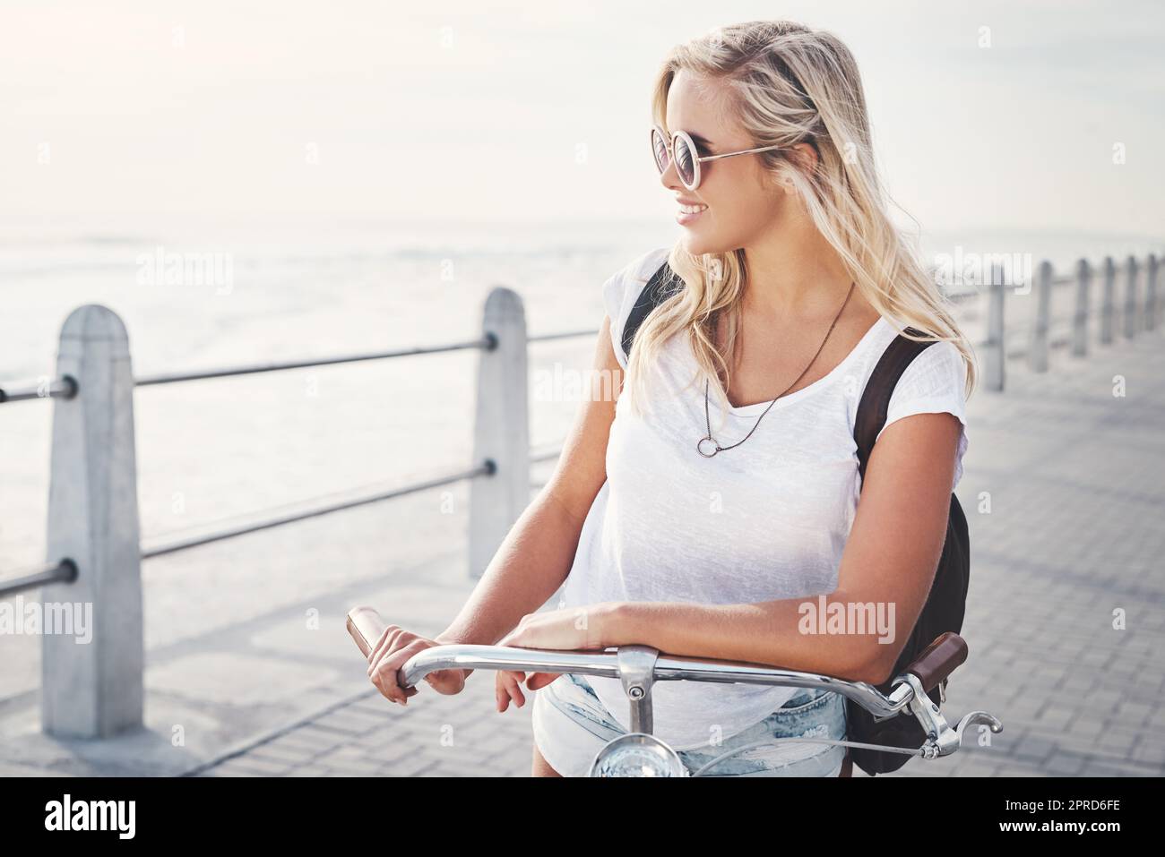 This is my favorite place to be. a beautiful young woman out on the promenade with her bicycle. Stock Photo
