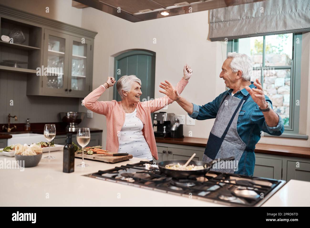 Good food puts everyone in a good mood. a senior couple dancing while cooking in the kitchen at home. Stock Photo