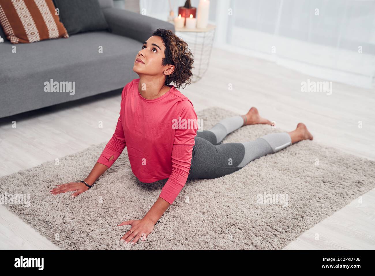 My back feels amazing when I do this pose. Full length shot of an attractive young woman doing yoga in her living and holding an upward facing dog position. Stock Photo