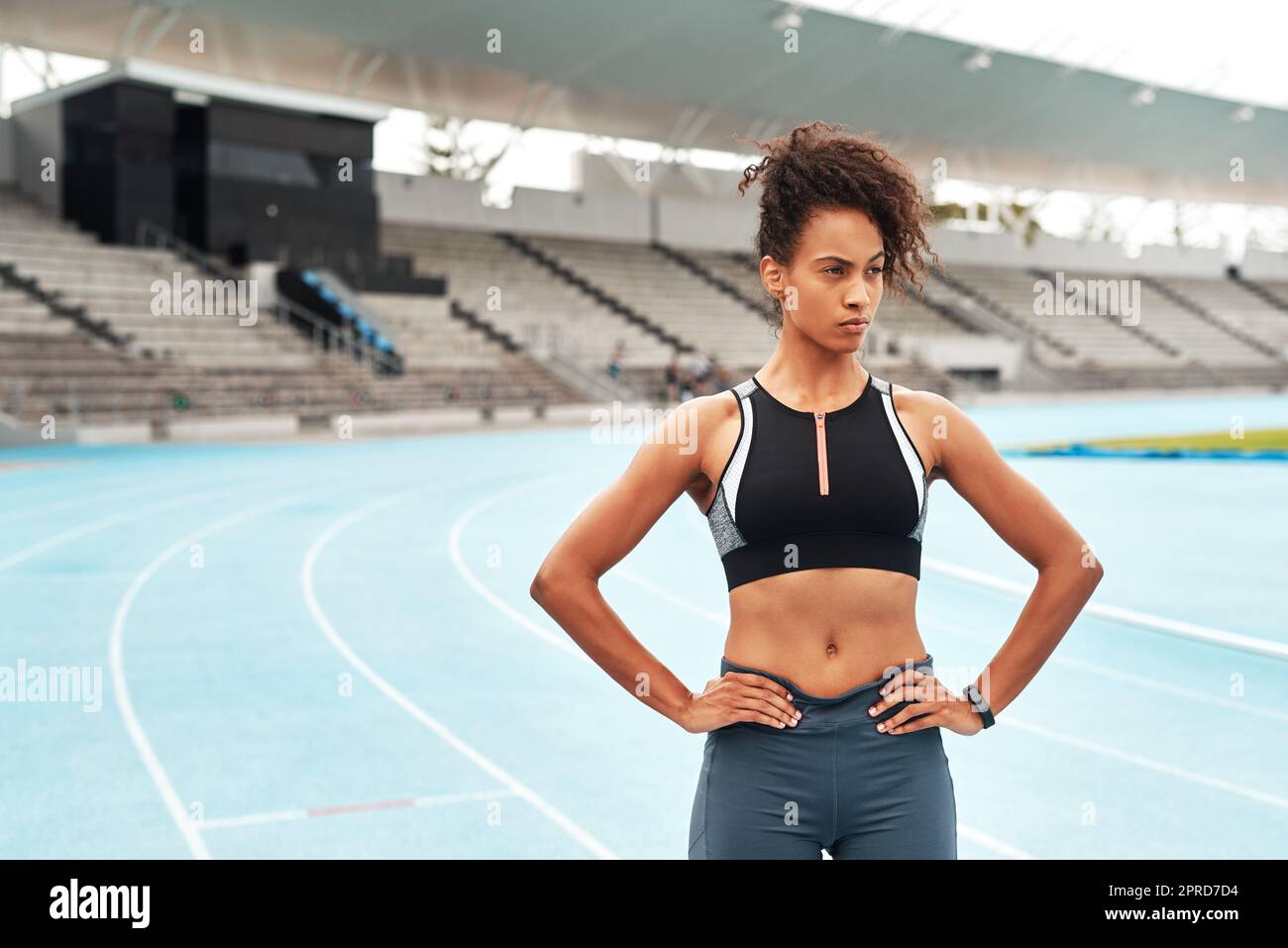 Im ready to train. an attractive young athlete standing akimbo after an outdoor track and field training session alone. Stock Photo