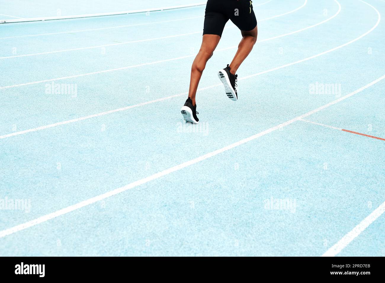 Building up my strength for the race. an unrecognizable athlete running along a track field alone during an outdoor workout session. Stock Photo