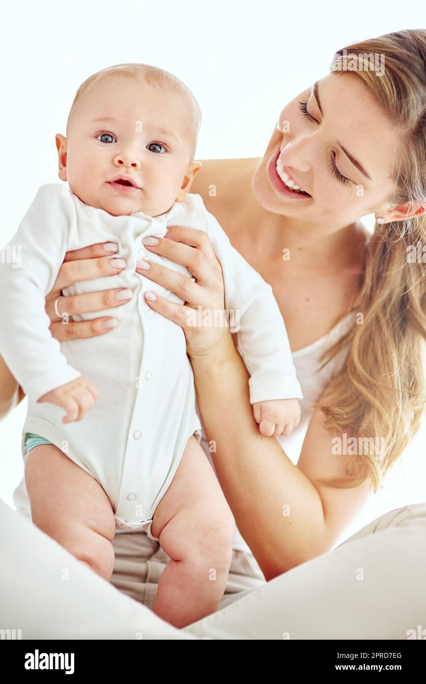 Portrait a happy mother bonding with her cute baby boy at home, enjoying fun moments of parenthood. Young female being affectionate and loving with her newborn, playing and spending time together Stock Photo