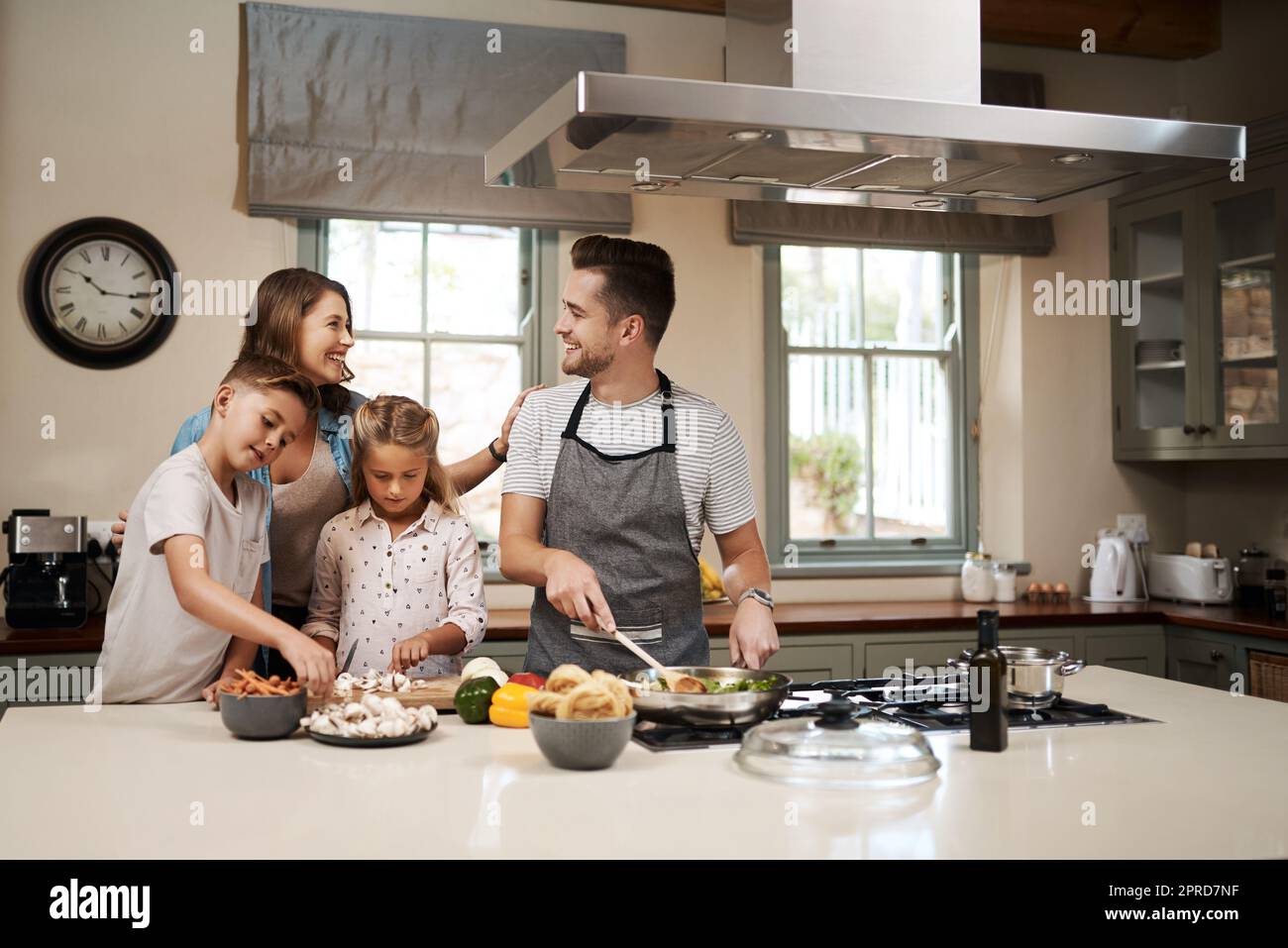 We love weekends because then we get to do everything together. a young family cooking in the kitchen. Stock Photo