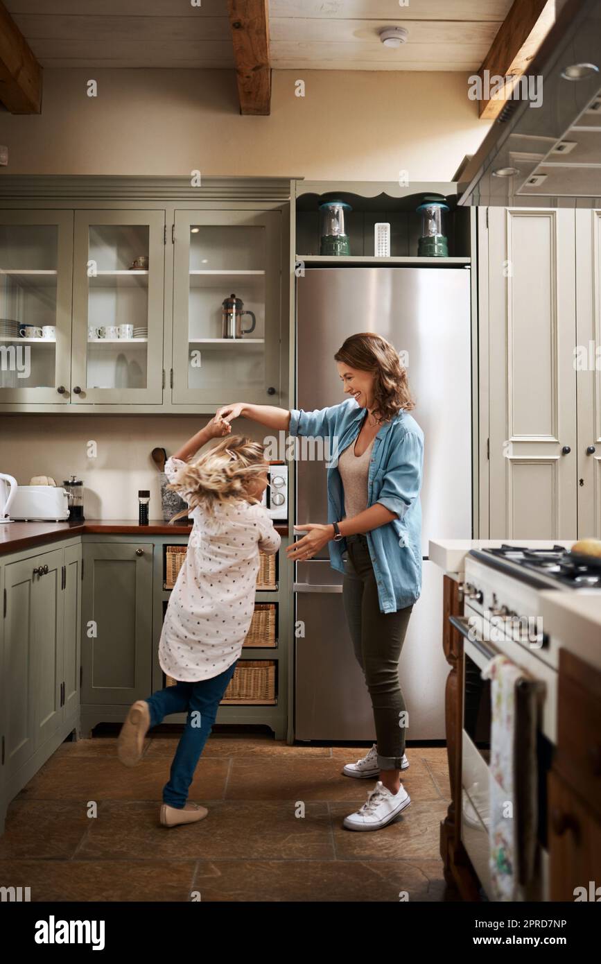 I just want to see her light up with joy. a young girl and her mother dancing in the kitchen at home. Stock Photo