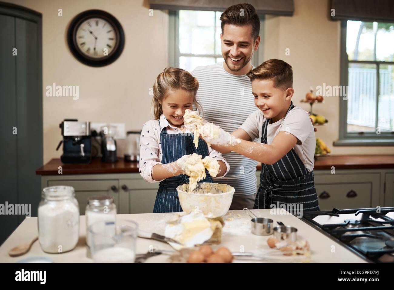 Im happy when my kids are happy. a man and his two children baking in the kitchen at home. Stock Photo