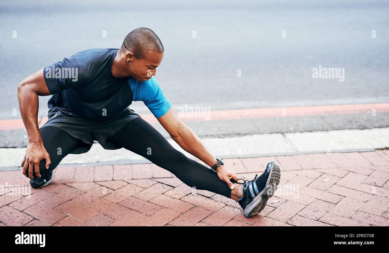 I can never stress the importance of stretching. Full length shot of a handsome young sportsman stretching and warming before exercising outdoors in the city. Stock Photo