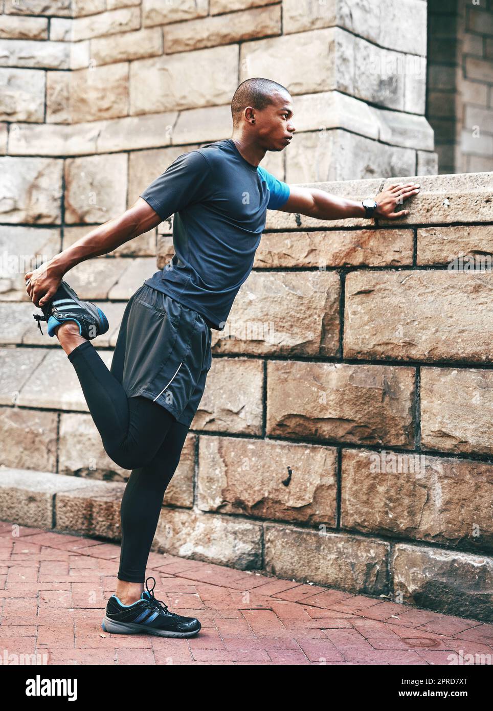 Hes just getting warmed up. Full length shot of a handsome young sportsman stretching and warming before exercising outdoors in the city. Stock Photo