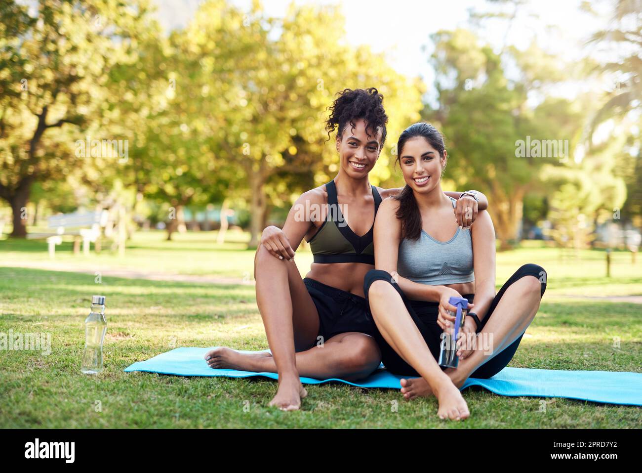 Together, we can accomplish anything. Full length portrait of two attractive young women sitting close to each other and smiling while in the park. Stock Photo