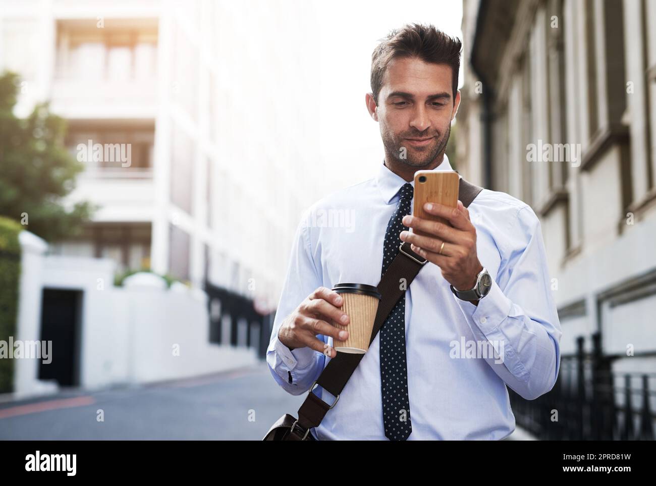 Talking on the phone this early in the morning. a handsome young businessman texting on his cellphone while heading to work in the morning. Stock Photo