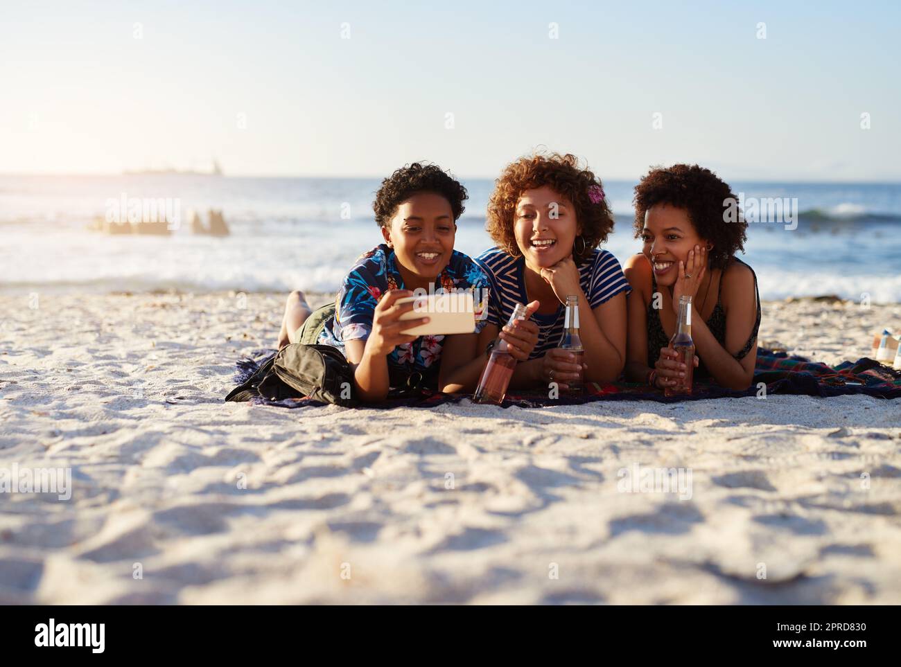 Selfie time. an attractive young trio of women laying down on the beach and  taking selfies together during the day Stock Photo - Alamy