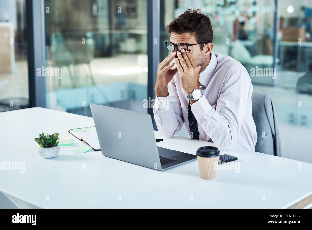 Work stress is getting to him. a businessman looking stressed while sitting at his desk. Stock Photo