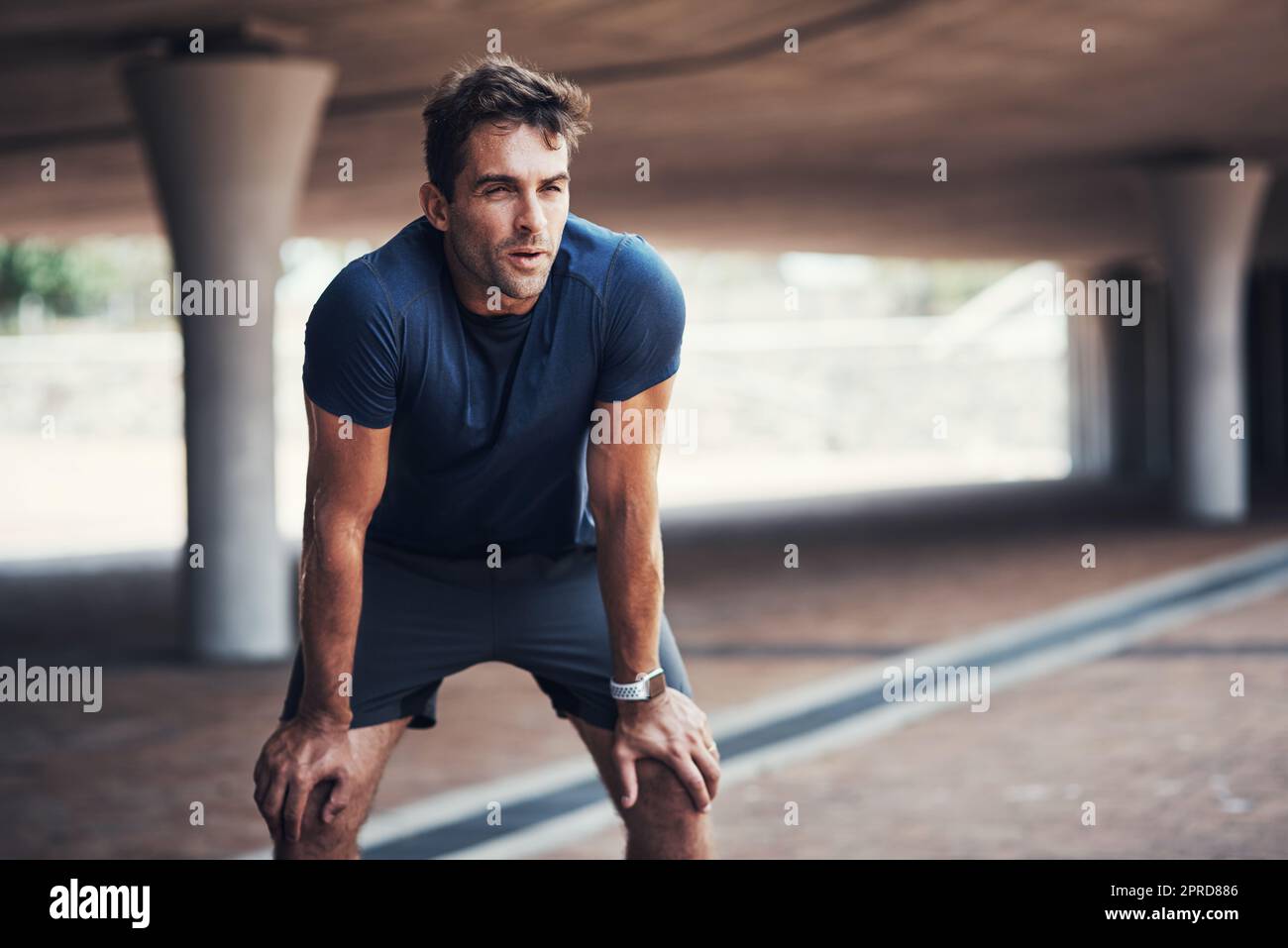 I just need to catch my breath real quick. a sporty young man taking a break while exercising outdoors. Stock Photo