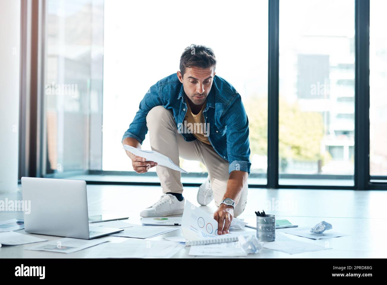 Bold ideas need lots of space to dwell. a young businessman brainstorming with paperwork on a floor in an office. Stock Photo