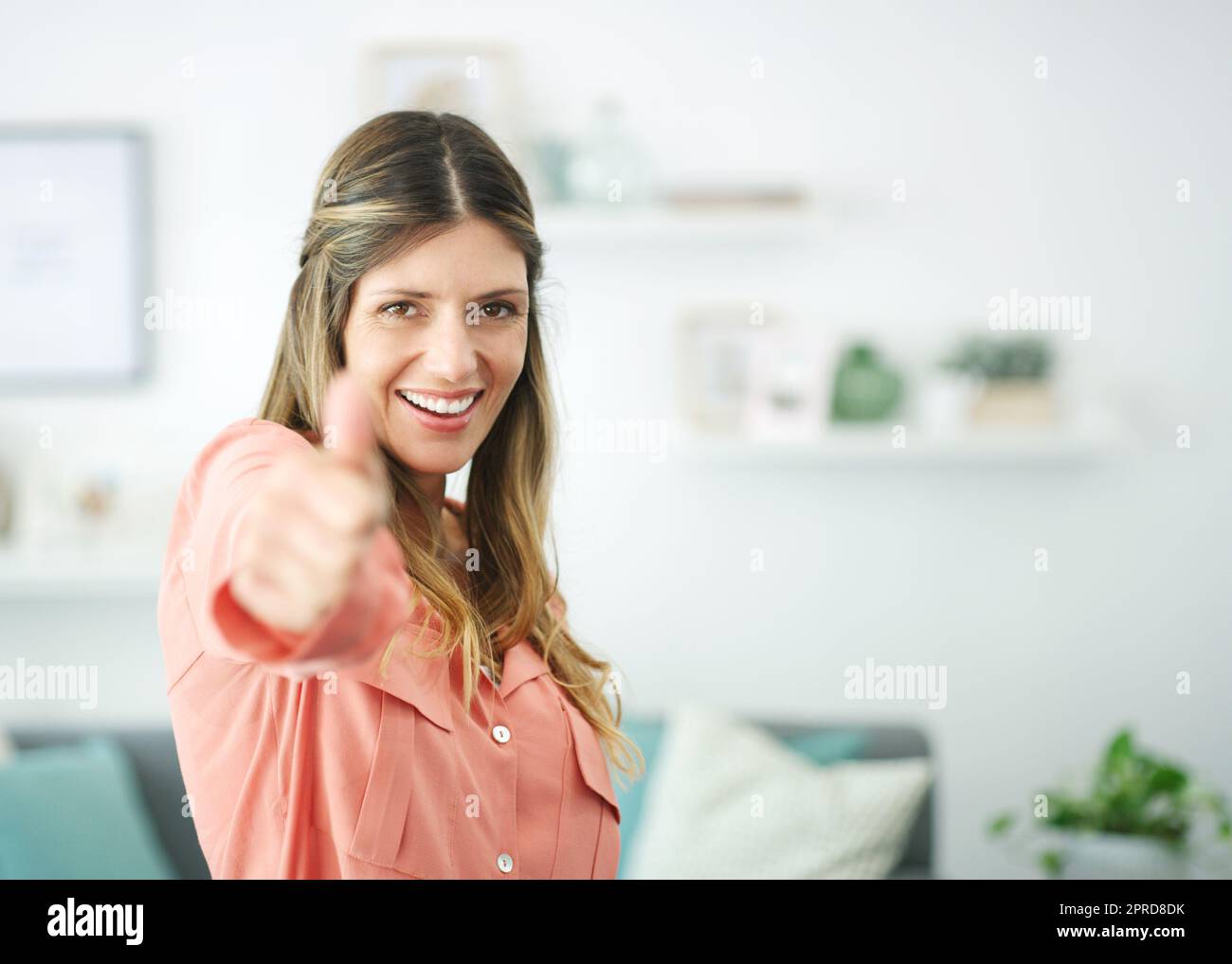 Its a yes from me. a woman showing thumps up while relaxing at home. Stock Photo