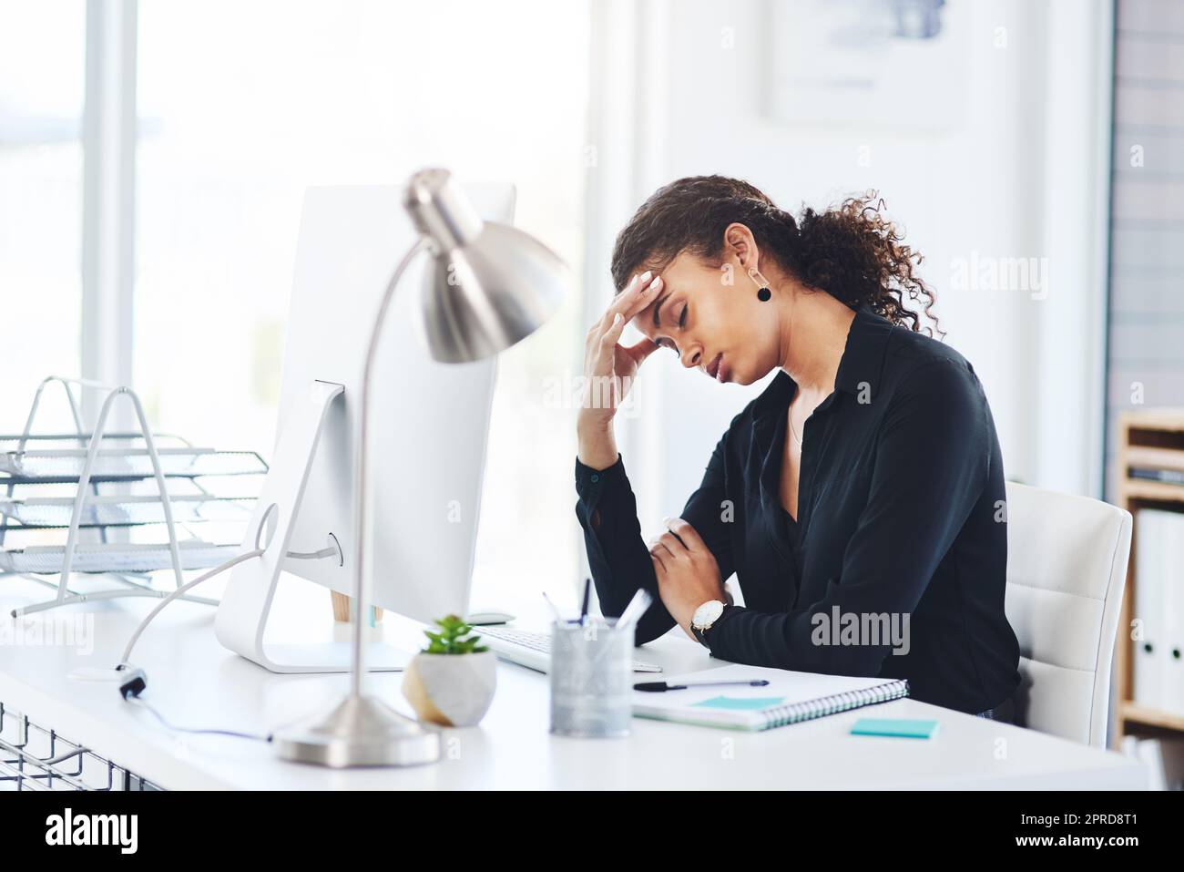 How many more challenges do I have to face today. a young businesswoman looking stressed out while working in an office. Stock Photo