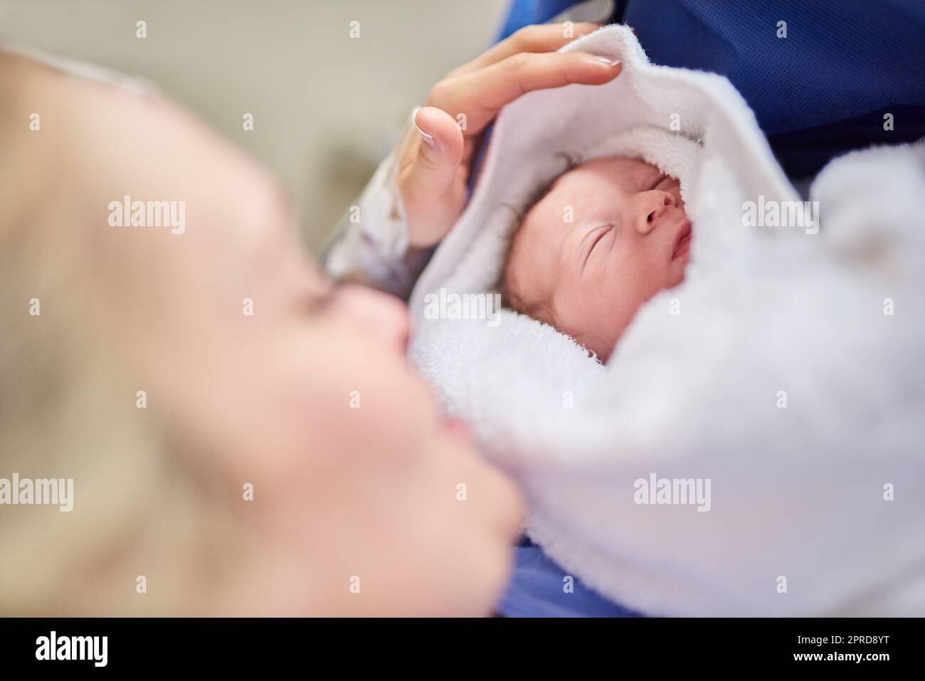 Shes so tiny and beautiful. an adorable baby girl sleeping in her mothers arms in hospital. Stock Photo