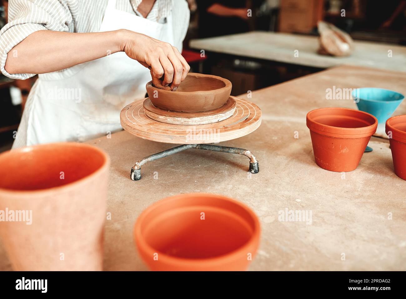 Its not just a bowl, its art. an unrecognizable woman shaping a clay pot in her workshop. Stock Photo