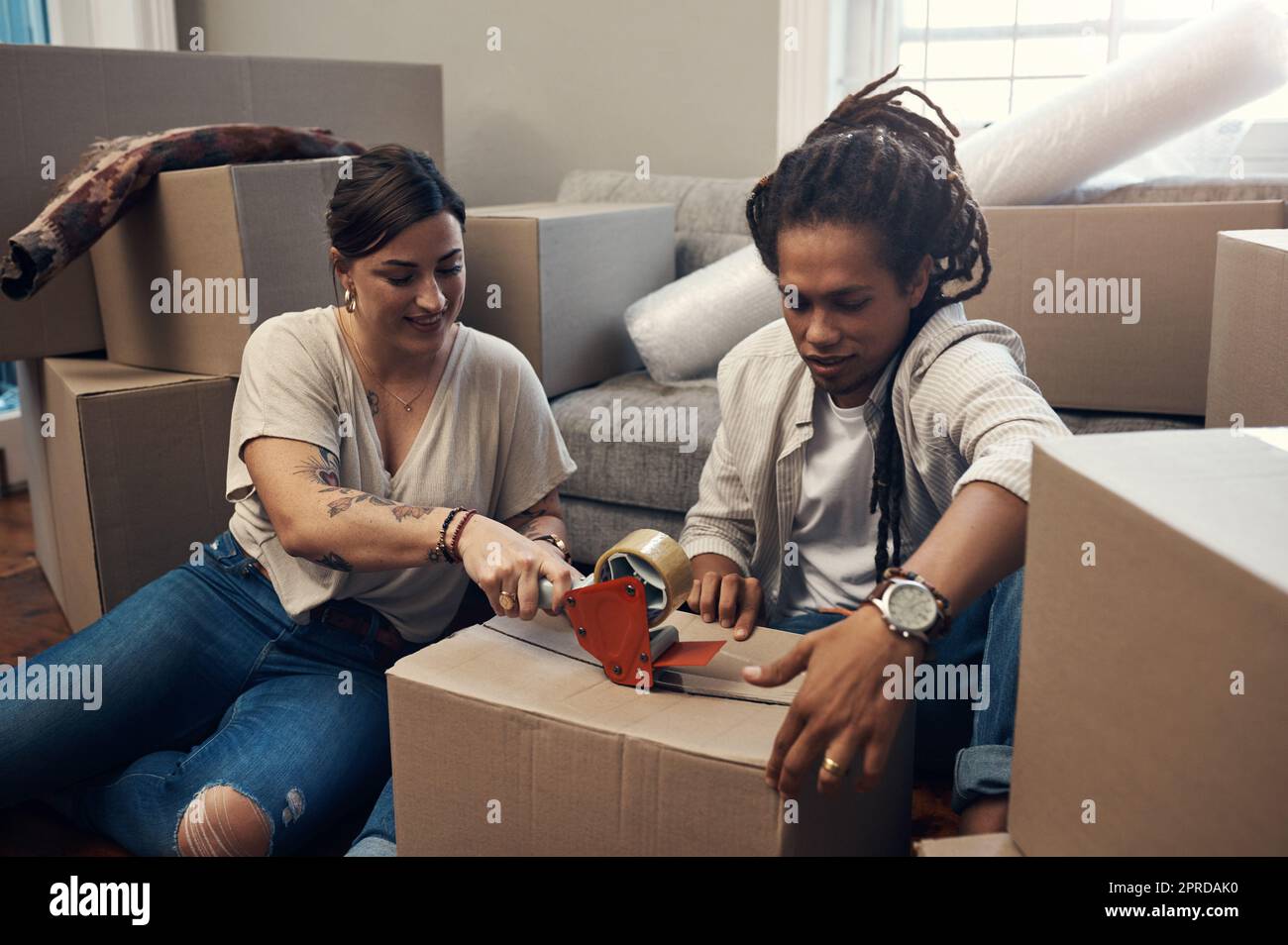 This one is ready to go. a young couple taping up boxes at home. Stock Photo