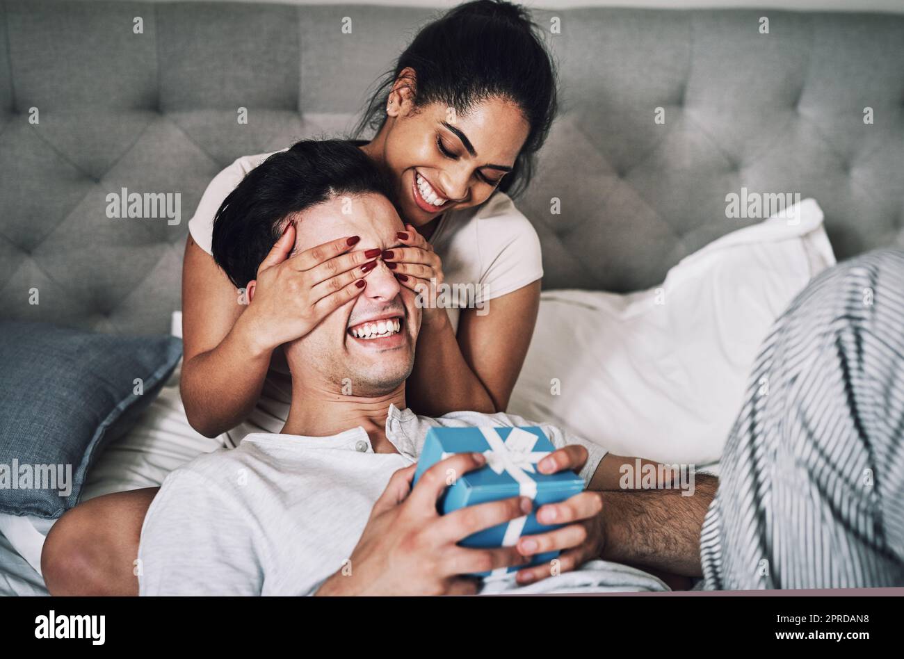 I tricked him into thinking that I forgot his birthday. a woman covering her boyfriends eyes while surprising him with a gift. Stock Photo