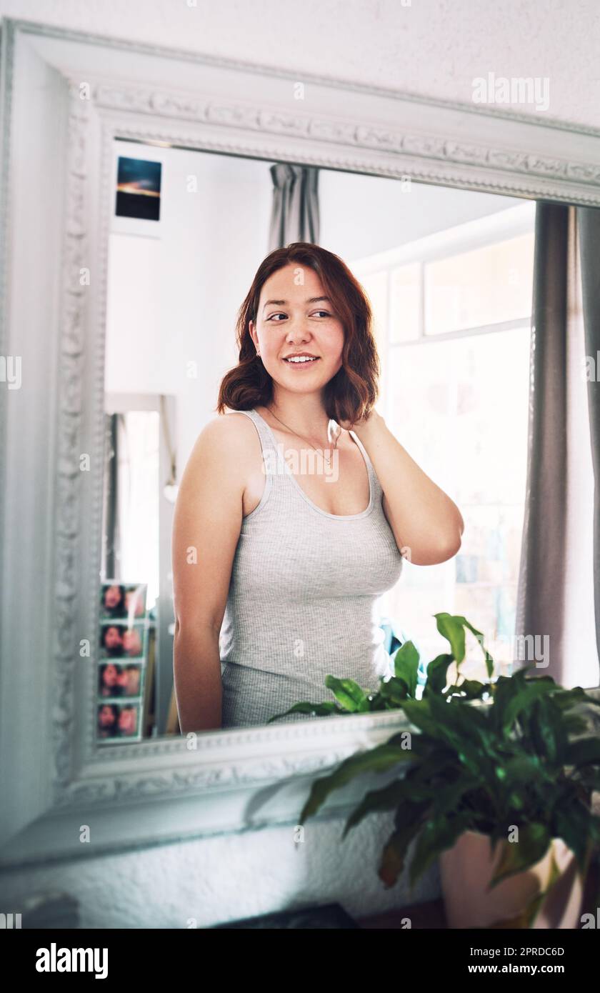 All I see is a pretty girl in this mirror. an attractive young woman admiring herself while standing in front of the mirror in her bedroom at home. Stock Photo