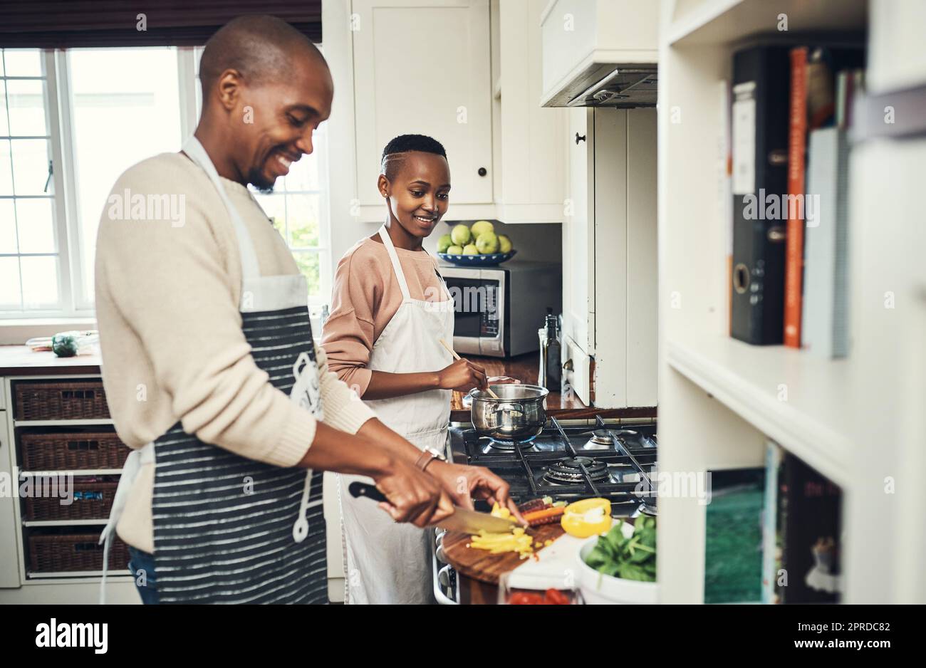 A meal prepared with love is always better. an affectionate young couple preparing dinner in their kitchen. Stock Photo