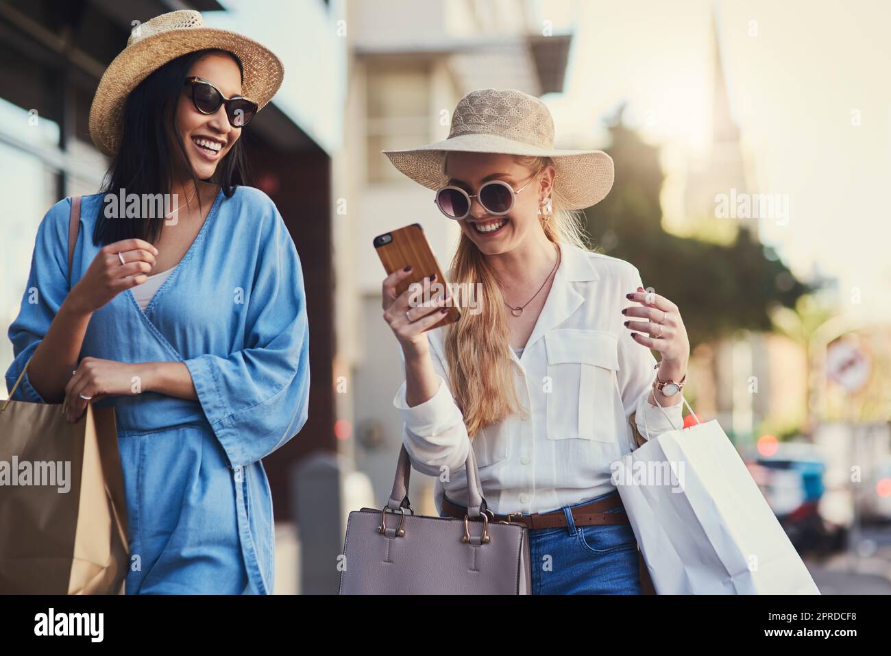 Girl I think my crush just responded. an attractive young woman smiling at her smartphone while walking with her best friend during a shopping spree in the city. Stock Photo