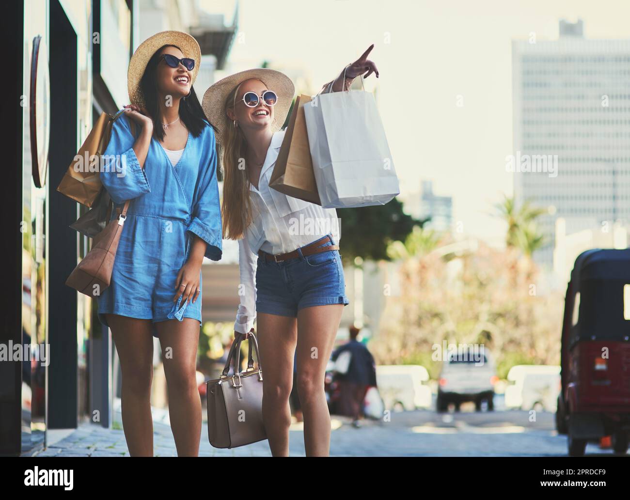 Thats where the sale is. an attractive young woman pointing towards something while walking with her best friend during a shopping spree in the city. Stock Photo