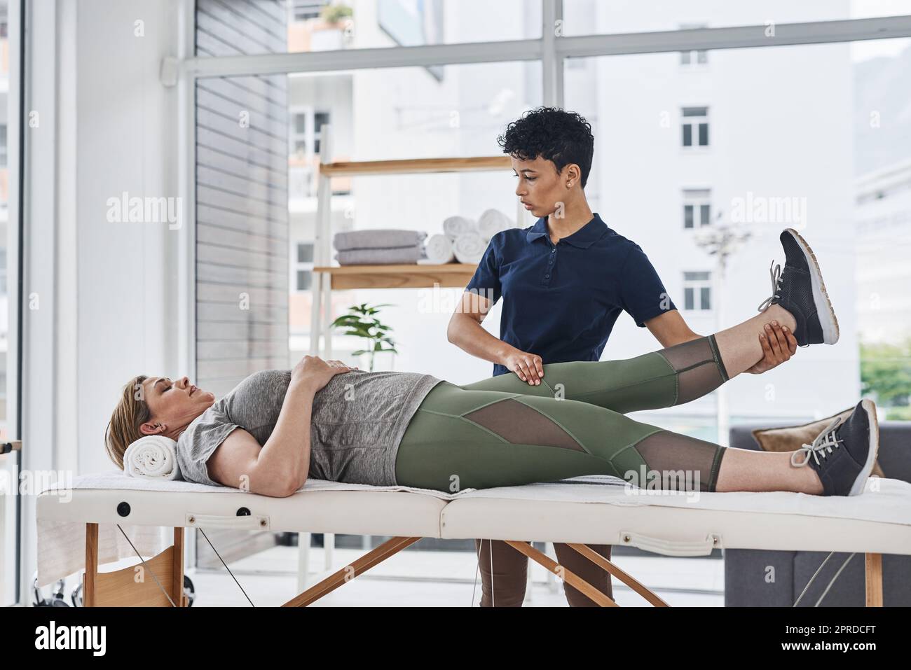Getting back to full fitness one stretch at a time. a young physiotherapist doing leg exercises with her patient inside her office at a clinic. Stock Photo