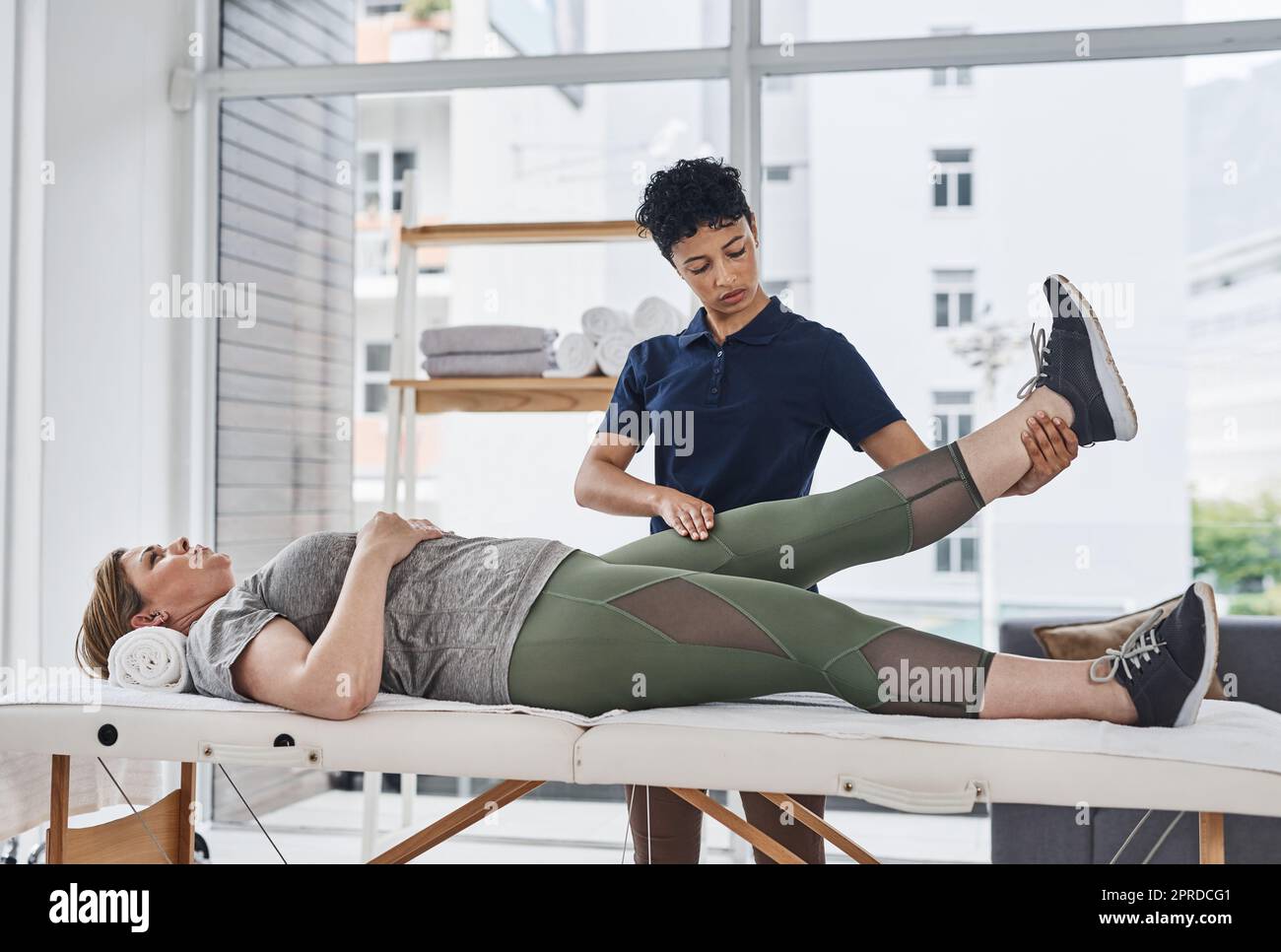 Shes committed to bringing you back to full health. a young physiotherapist doing leg exercises with her patient inside her office at a clinic. Stock Photo