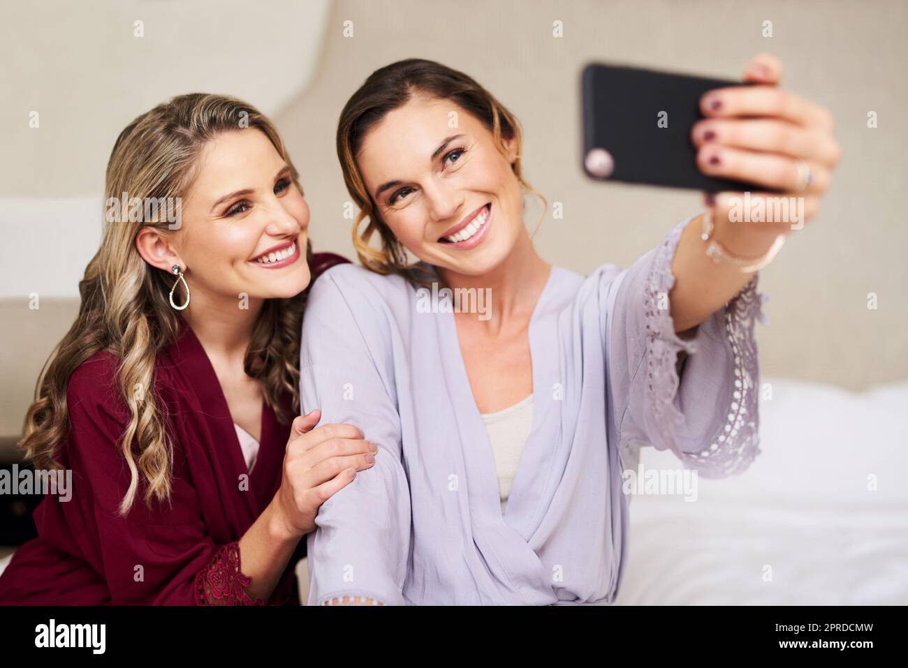 The days finally here. a beautiful young bride and her best friend taking a selfie together in their dressing room before the wedding. Stock Photo