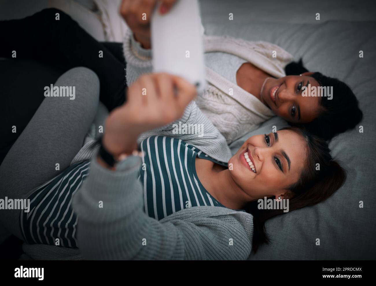 Sleepover selfie vibes. two young women lying taking selfies while lying on a bed. Stock Photo