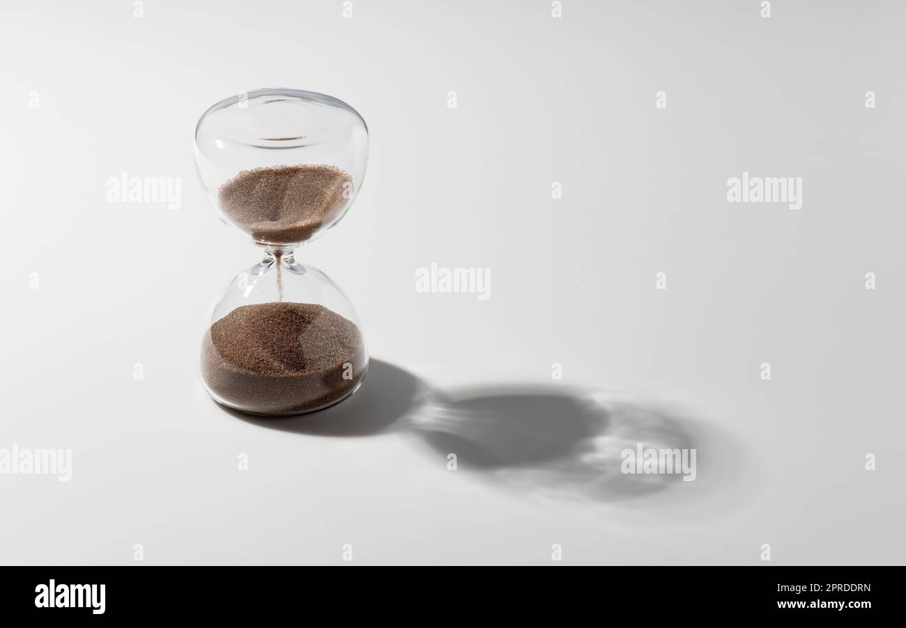 An hourglass placed on a white background. Stock Photo