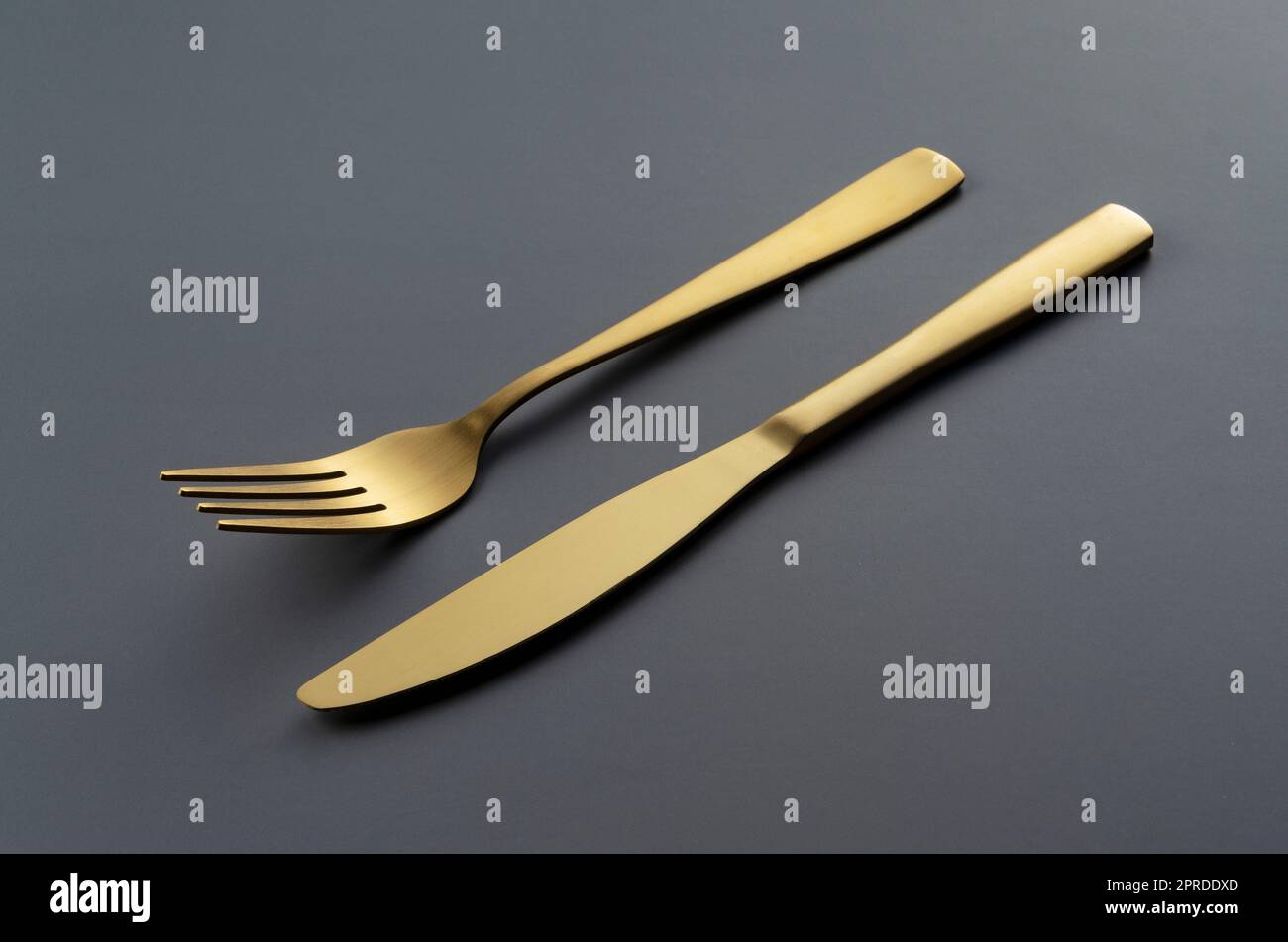 https://c8.alamy.com/comp/2PRDDXD/gold-knives-and-forks-set-against-a-black-background-2PRDDXD.jpg