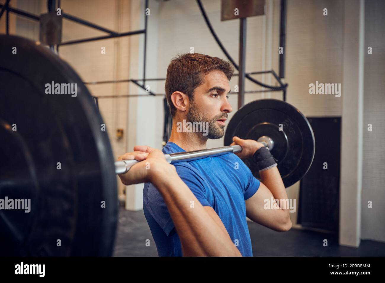 No quit, I want to lift. a handsome young man lifting weights while working out in the gym. Stock Photo