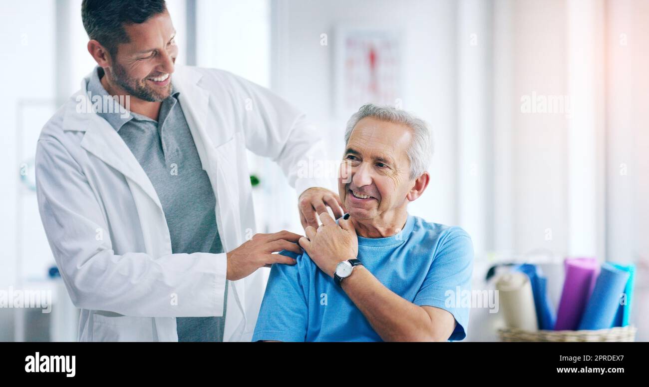I can already feel the pain going away. a male doctor doing some physiotherapy with a senior patient. Stock Photo