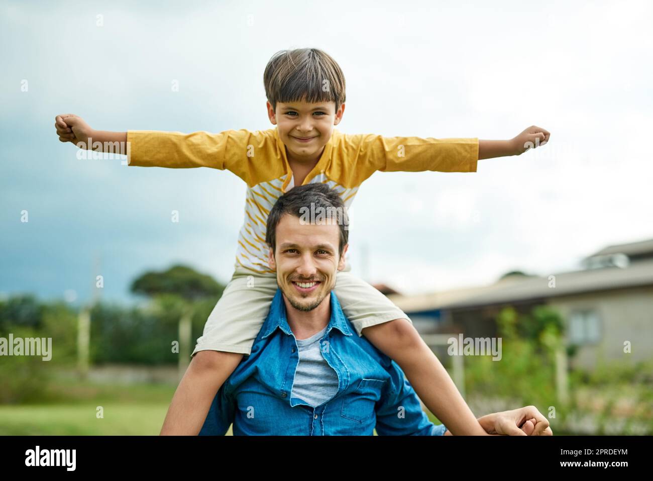 Hes flying high with his poppa. Portrait of a cheerful father carrying his young son on his shoulders outdoors. Stock Photo