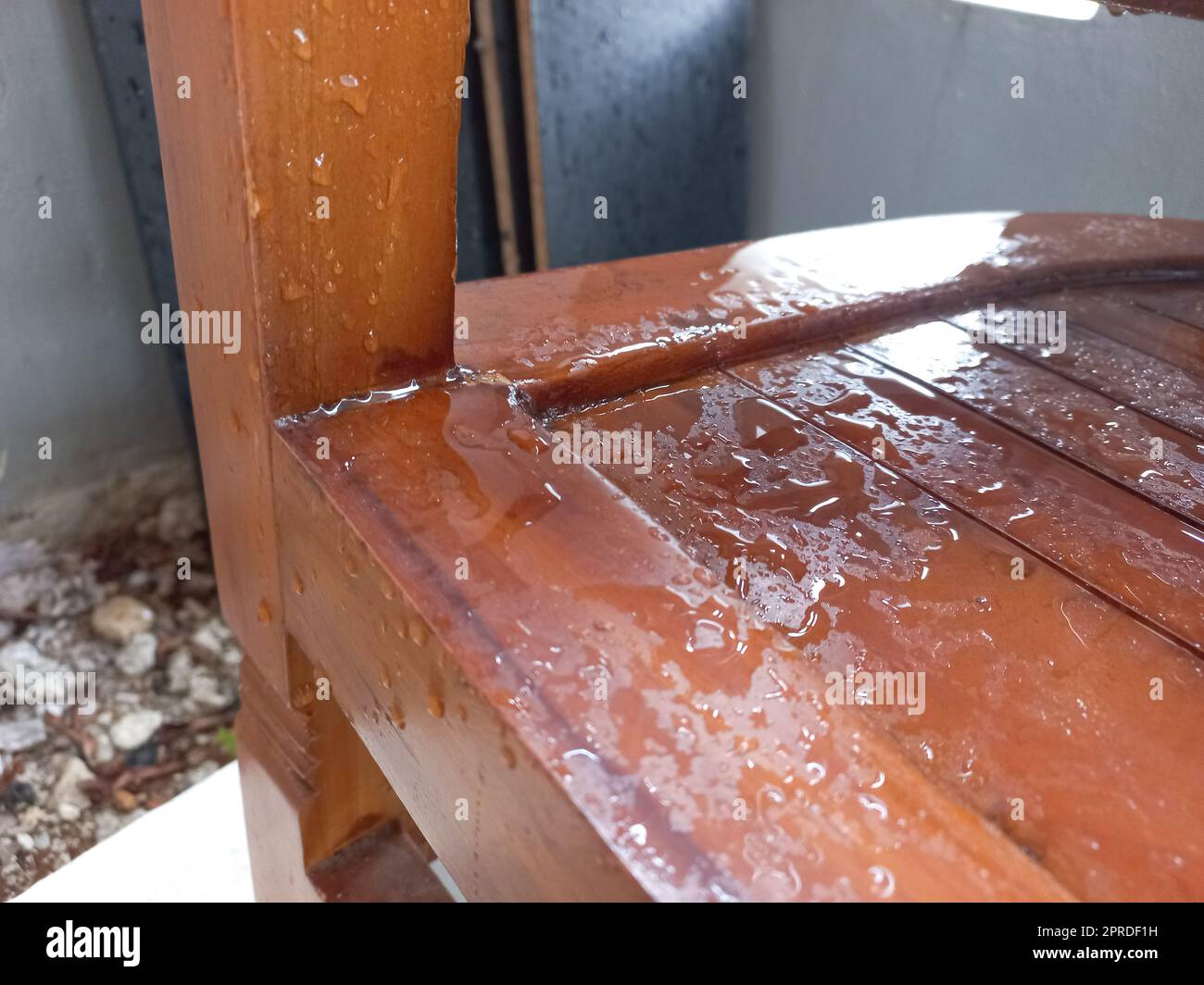 A chair made of teak wood with raindrops that wet the chair Stock Photo