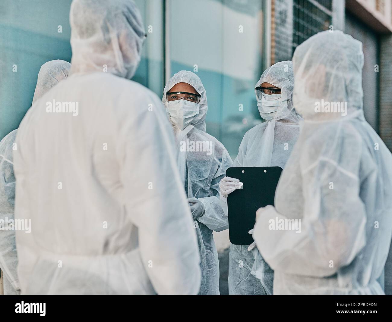 Health and safety personnel in protective gear ready to fight a virus, outbreak or pandemic. Hazmat wearing doctor, nurse and team or group of medical and healthcare professional at a quarantine site Stock Photo