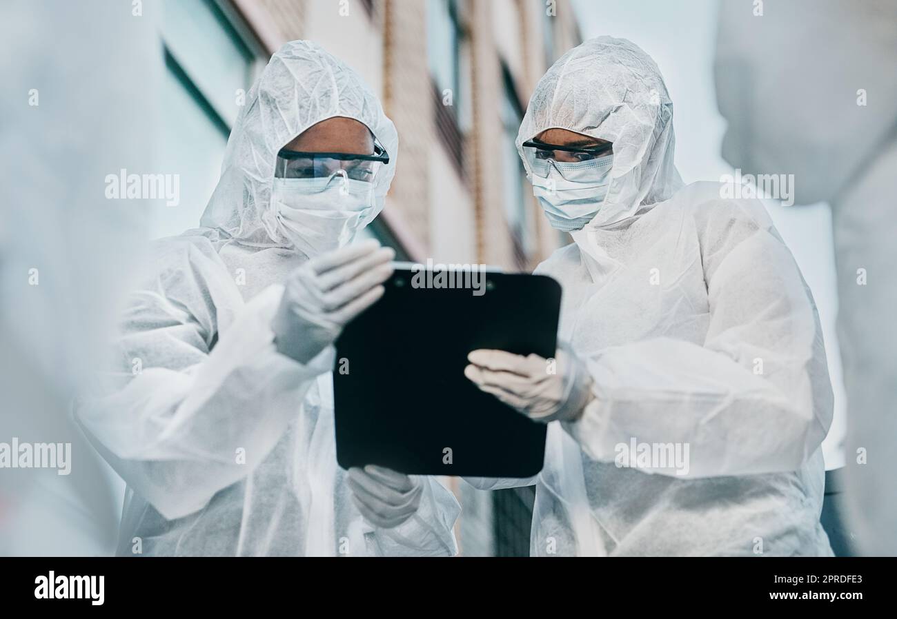 Hazmat wearing doctor and nurse working as a medical team and healthcare professionals at a quarantine site. Health and safety colleagues in protective gear ready to fight a virus or pandemic Stock Photo