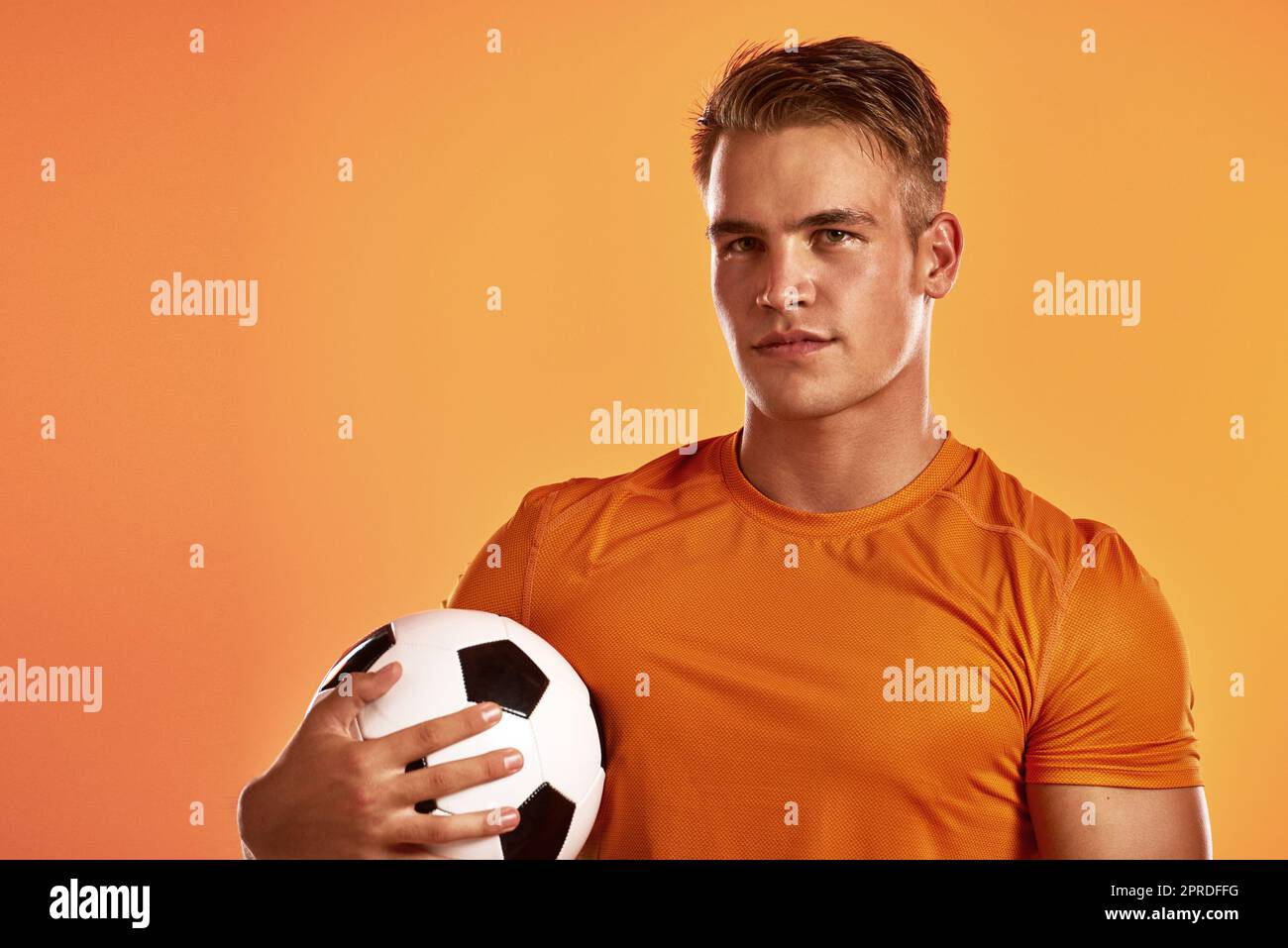 See you on the field. Studio portrait of a handsome young male soccer player posing against n orange background. Stock Photo