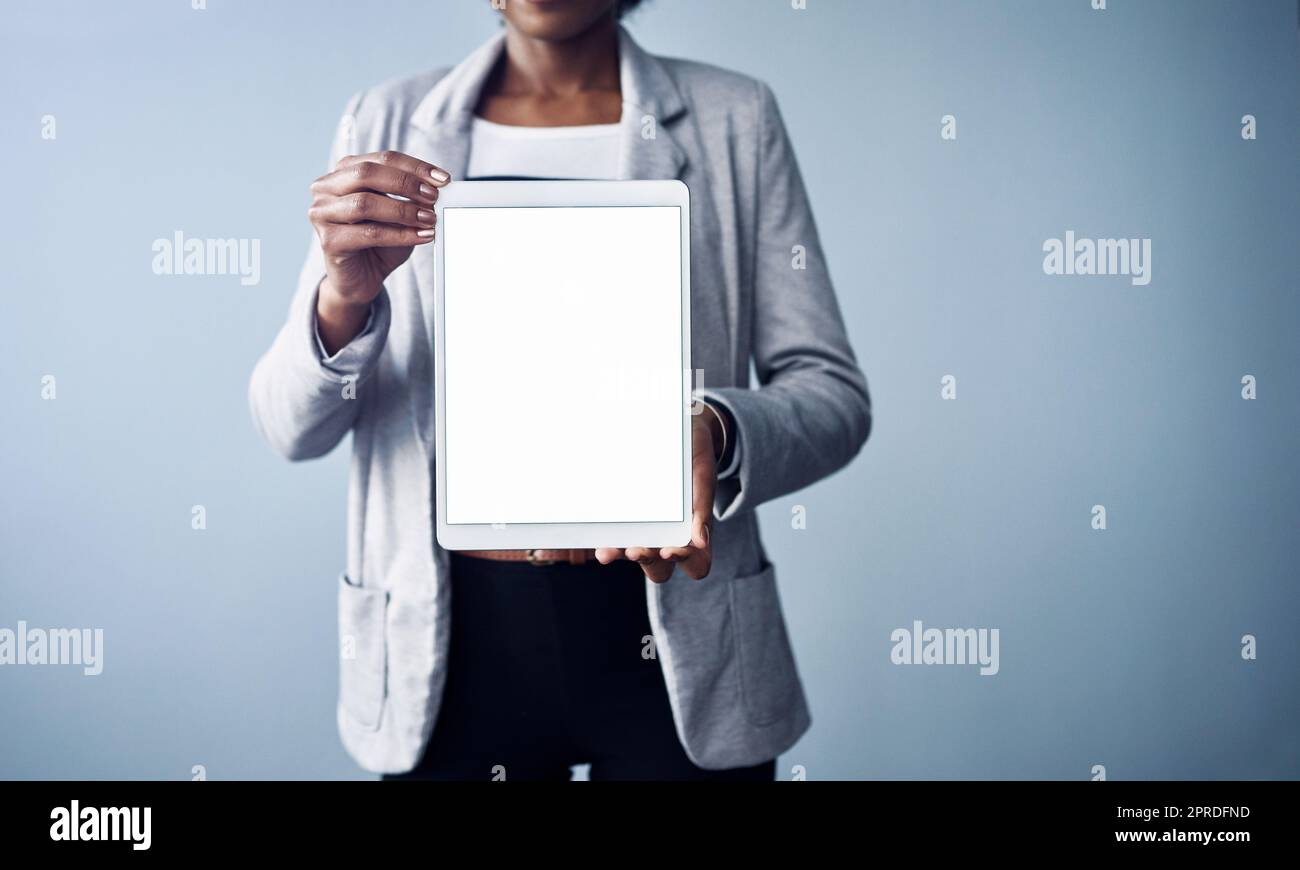 Woman holding a white screen tablet looking professional mockup. Young and isolated black business corporate executive standing alone with blank digital device against a blue background copyspace Stock Photo