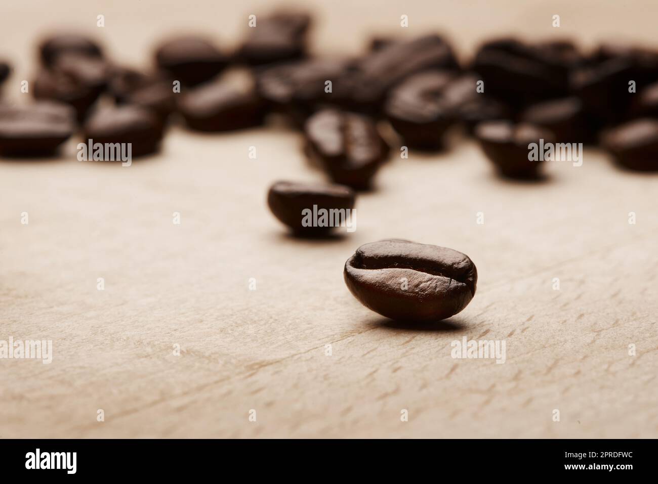 Coffee brings out the best in us. Still life shot of coffee beans on a wooden countertop. Stock Photo