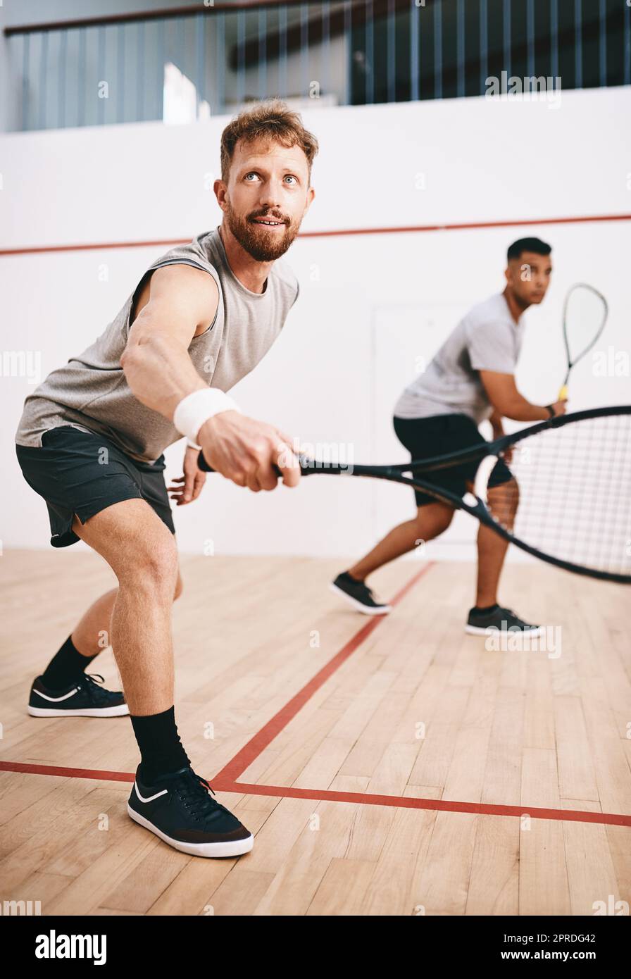 He only has eyes for the ball. two young men playing a game of squash