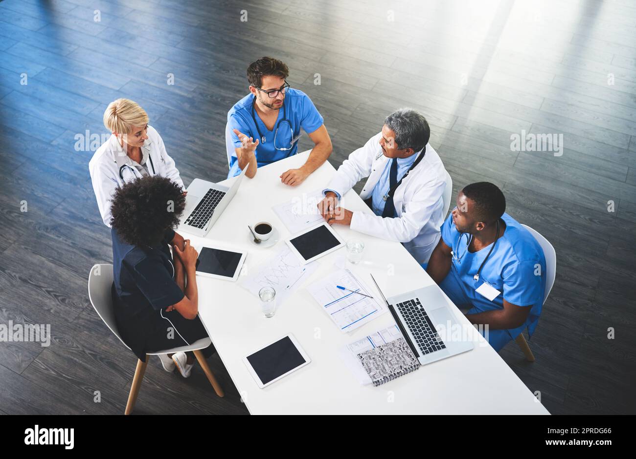 Doctors, medical professionals and workers talking in a meeting, discussing a strategy and making plans while working at hospital. Clinic employees having discussion in seminar, workshop or training Stock Photo