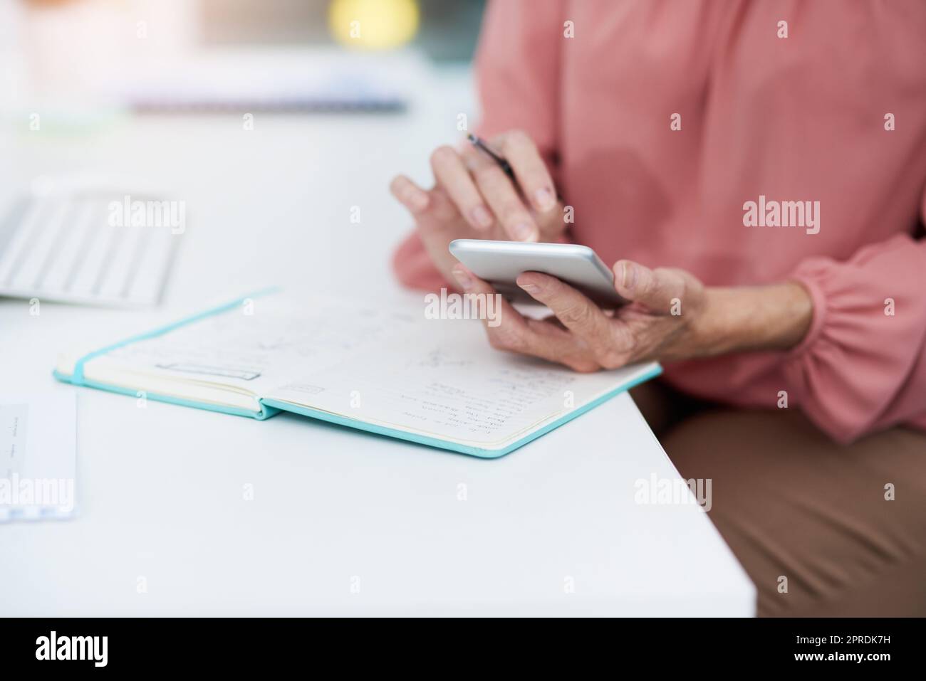 I hope this number still works. an unrecognizable mature woman writing down details from her cellphone to her diary at work. Stock Photo