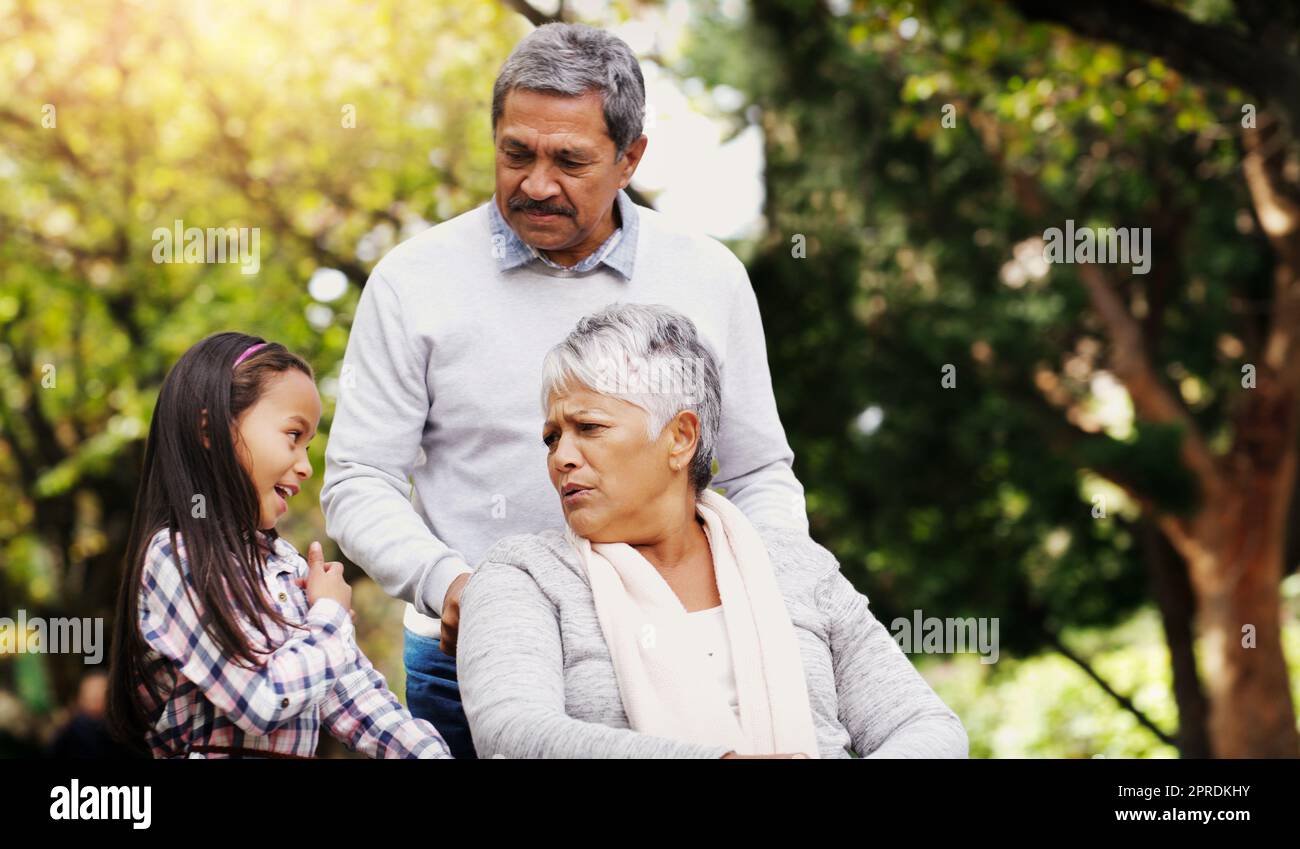 She always has interesting stories to tell us. an adorable little girl spending some time with her grandparents at the park. Stock Photo