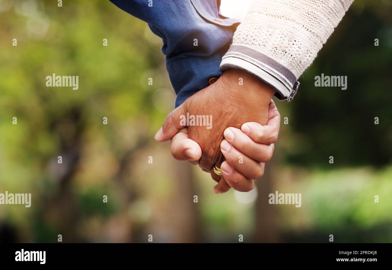 Our bond remains strong throughout all these years. Closeup shot of an unrecognizable senior couple holding hands in the park. Stock Photo