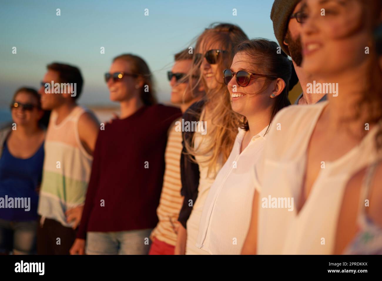 Its a summer to be remembered. a group of young friends standing together on the beach during the day. Stock Photo