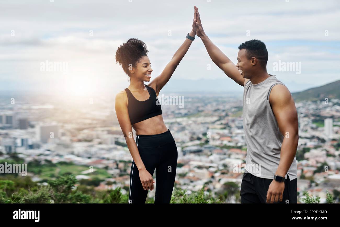 Theyll always be cheering each other on. a sporty young couple high fiving each other while exercising outdoors. Stock Photo